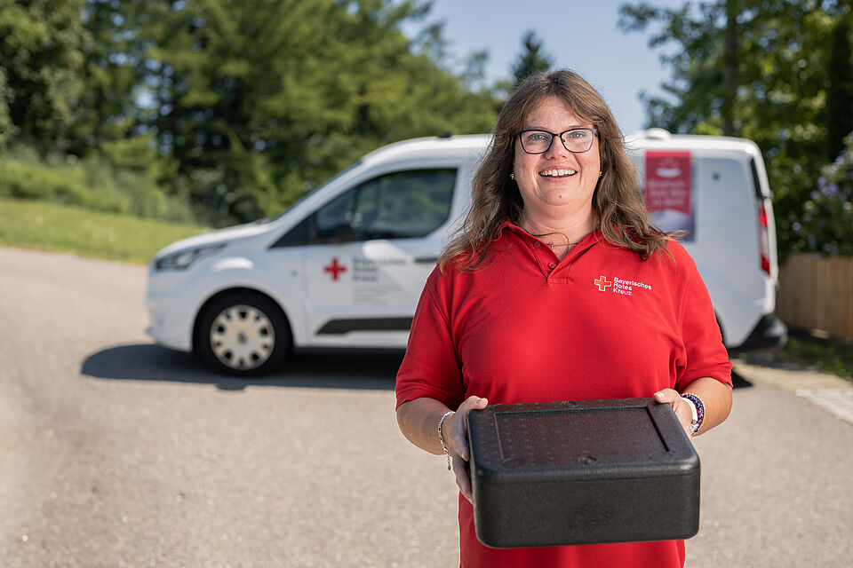 BRK Mitarbeiterin liefert warmes Mittagessen beim Menüservice im Landkreis Günzburg